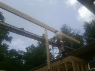 Carpenter setting a ridge beam over a new addition frame — Ice Dam Removal by Roofing Brothers in Webster
