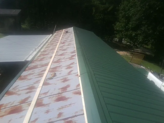 Old rusted panels beside newly installed green metal roofing — Wind Damage Roof Repair by Roofing Brothers in Webster