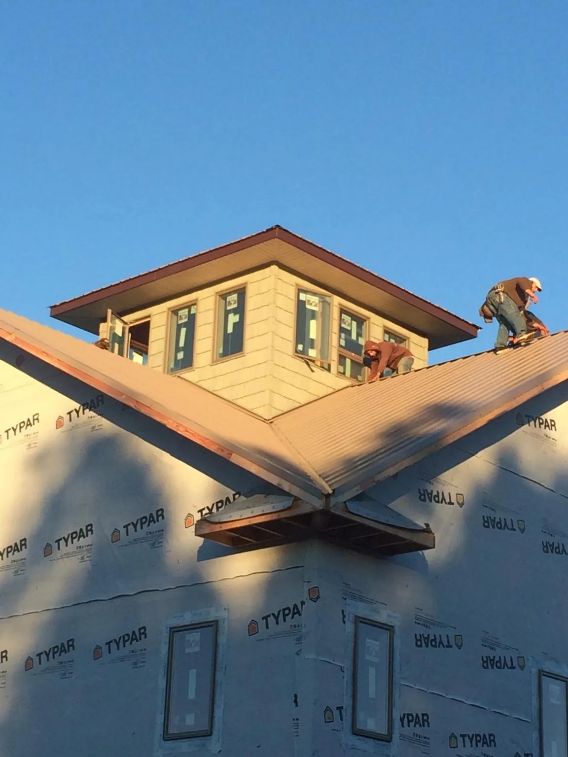 Roofers working around a rooftop cupola on a new metal roof at sunset — Roof Waterproofing in Webster by Roofing Brothers